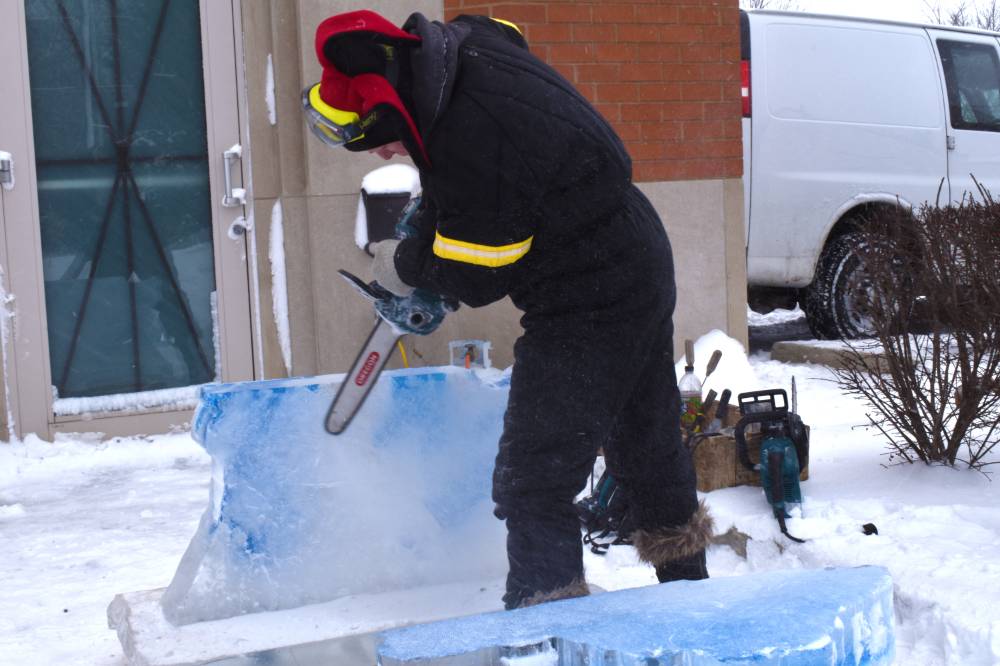 person with chainsaw against block of ice from behind